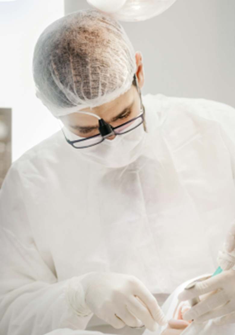 A dentist in full protective gear carefully treating a patient